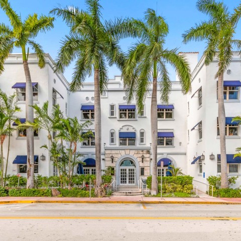 the hotel's white facade with palm trees on Collins Avenue